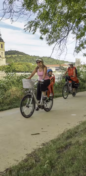Famille à vélo sur le halage de la Moselle à Pont-à-Mousson devant l'abbaye des Prémontrés