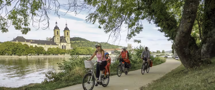 Famille à vélo sur le halage de la Moselle à Pont-à-Mousson devant l'abbaye des Prémontrés