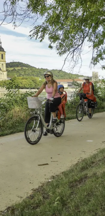 Famille à vélo sur le halage de la Moselle à Pont-à-Mousson devant l'abbaye des Prémontrés