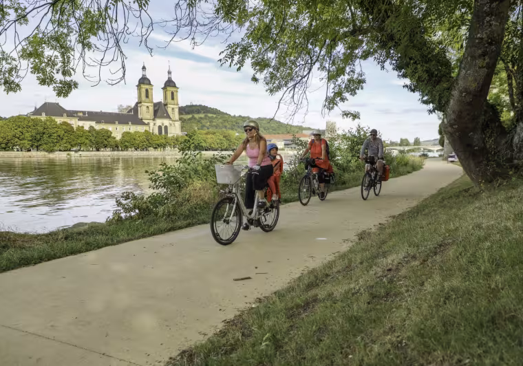 Famille à vélo sur le halage de la Moselle à Pont-à-Mousson devant l'abbaye des Prémontrés